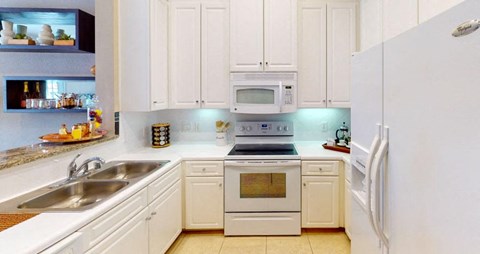 Bright kitchen with granite slab breakfast bar and white cabinets at Tuscany Court Apartments in Houston.