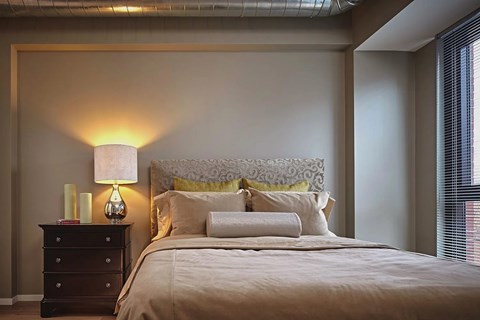 A bedroom with a bed, nightstand, and lamp.