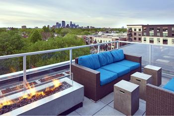 A patio with a blue couch and a fire pit.