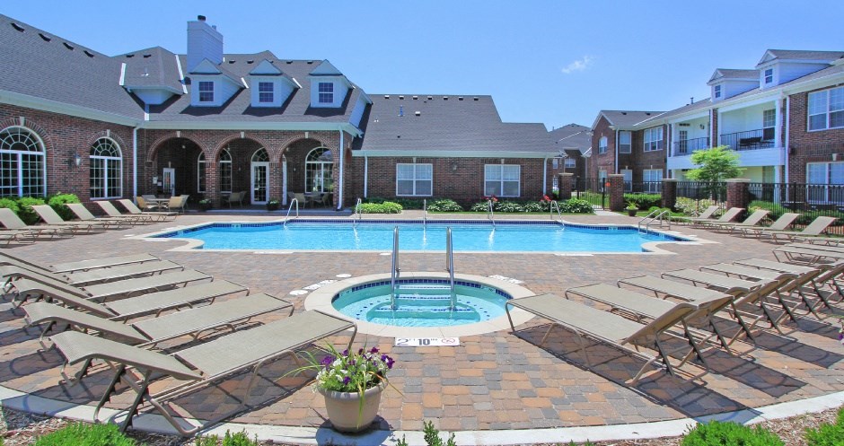 Luxury apartments with red brick exteriors, swimming pool, pool-side lounge chairs, beautiful landscaping, and scenic views at Rockledge Oaks Apartments in Lincoln, Nebraska