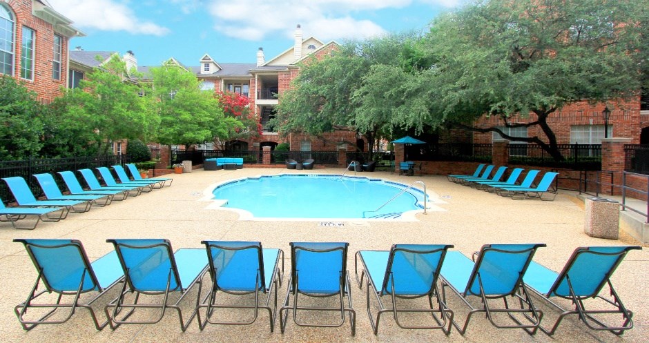 Gated community near the Galleria with brick exteriors, lush landscaping, two swimming pools with poolside lounge chairs, spa, and sauna at The Saxony Apartments