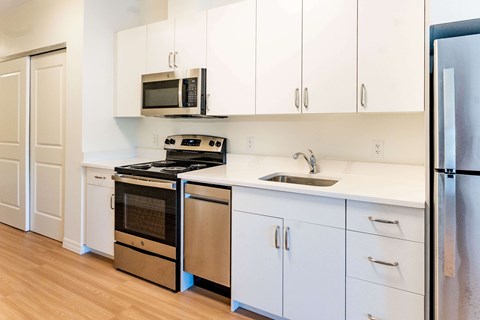 A kitchen with white cabinets and a black stove top oven.