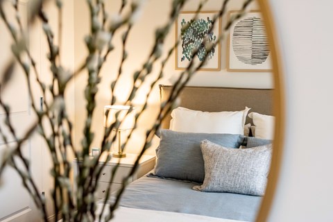 A bedroom with a bed, pillows, and a mirror.