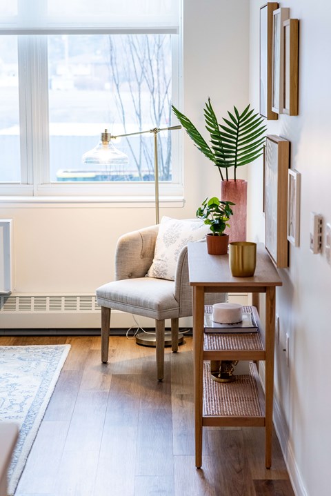A living room with a chair, a table, and a plant.