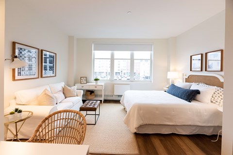 A bedroom with a large bed and a window overlooking a cityscape.