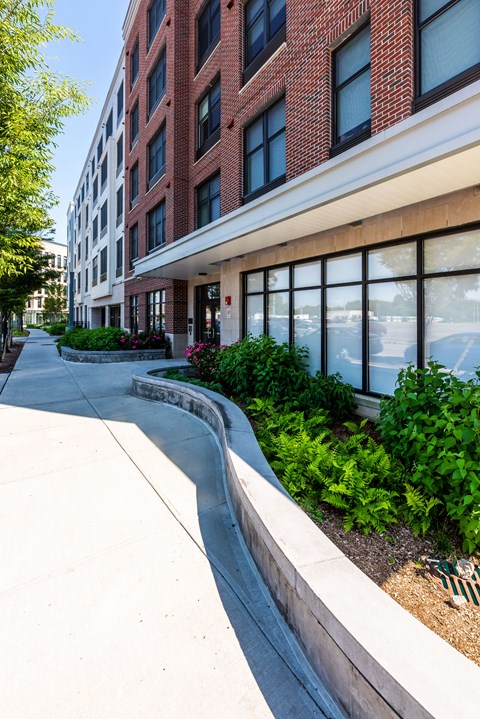 A red brick building with a white trim and a landscaped area in front.