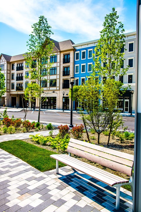 A bench is in front of a building with a tree in front of it.