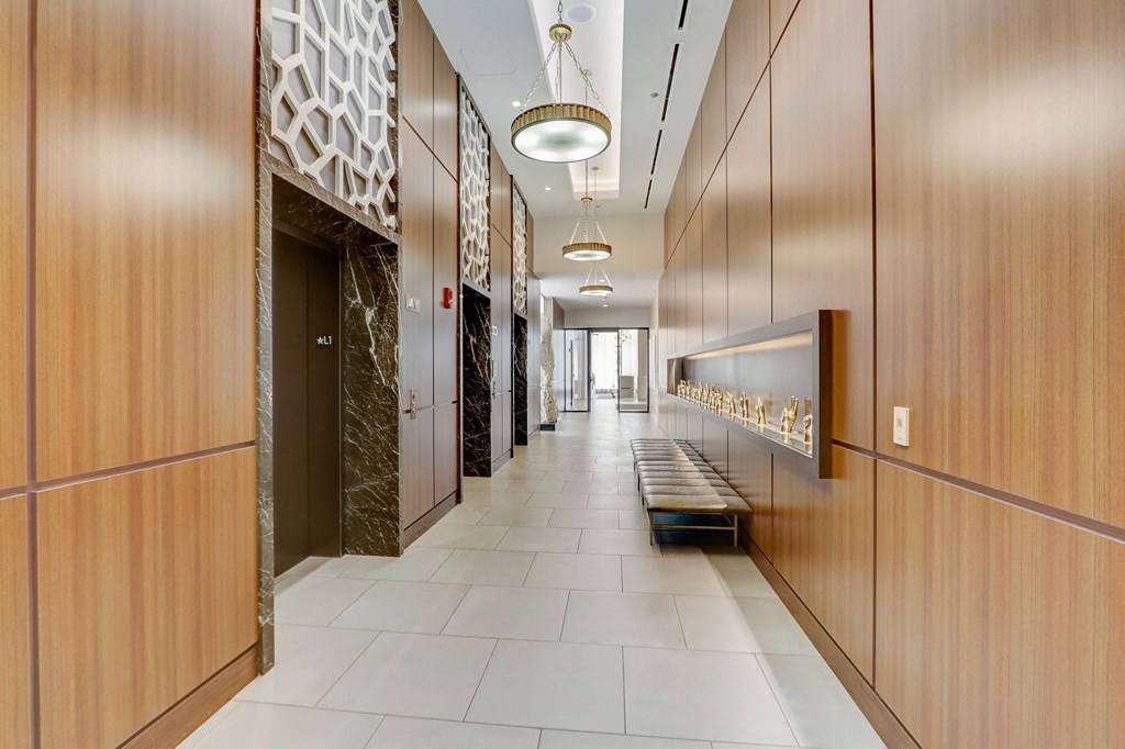 Long hallway with wood cabinets and a bench at The Apartments at Lincoln Common, Chicago, 60614