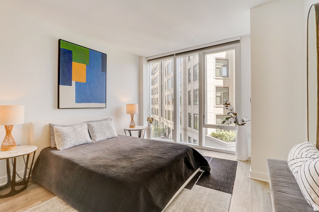 Bedroom with a large window and a large bed at The Apartments at Lincoln Common, Chicago