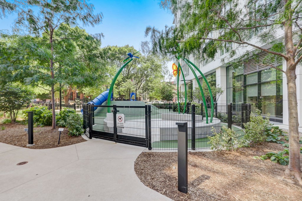 Playground with a large blue slide in front of a building at The Apartments at Lincoln Common, Chicago, 60614