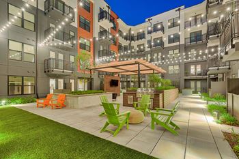 an outdoor patio with green chairs and a umbrella in an apartment building