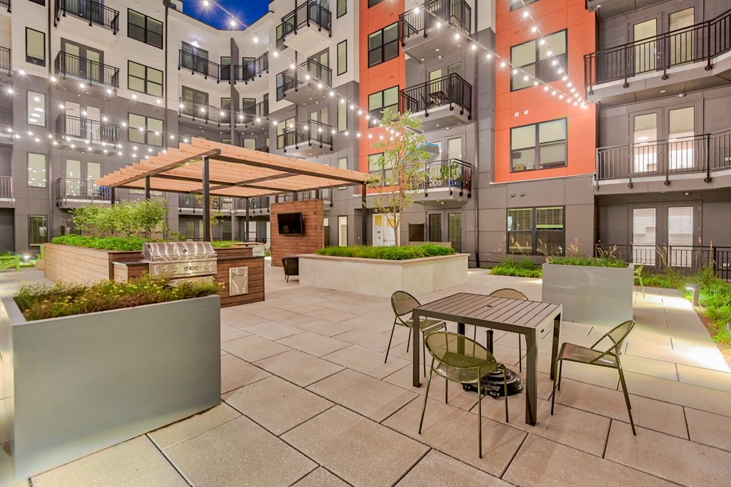 a patio with a table and chairs in front of an apartment building