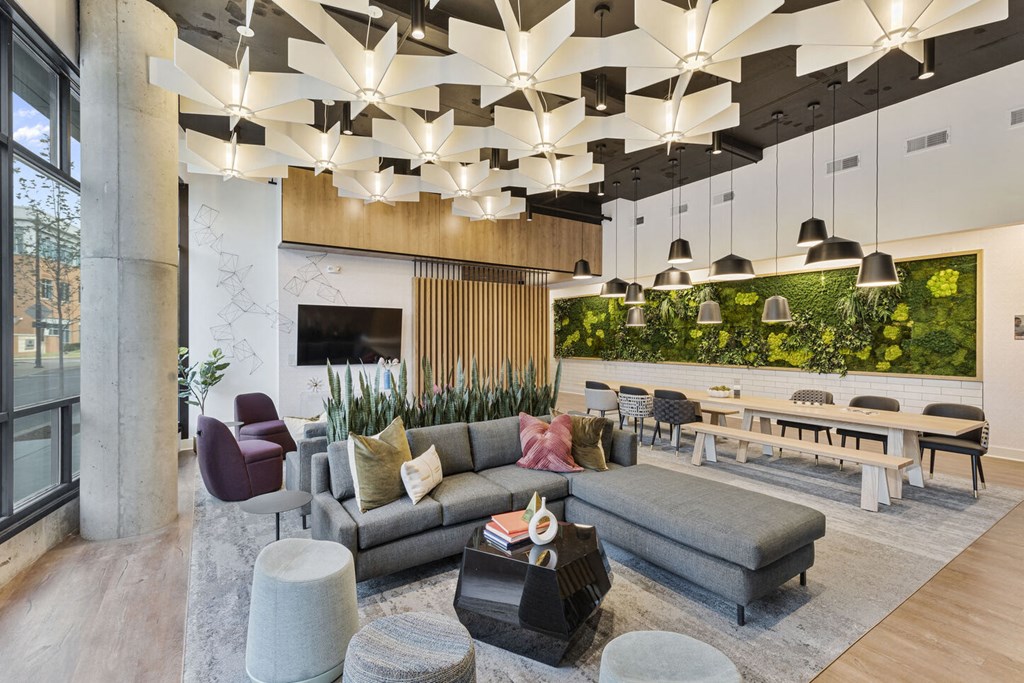a lobby with couches chairs and tables and a wall of plants