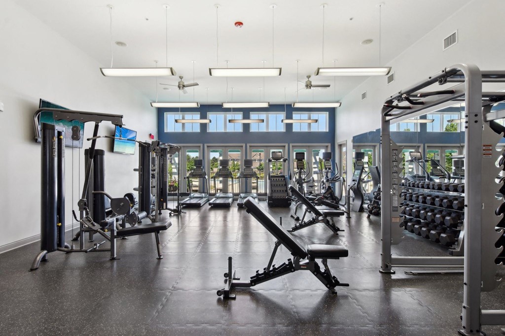 a gym with weights and other equipment on the floor and windows