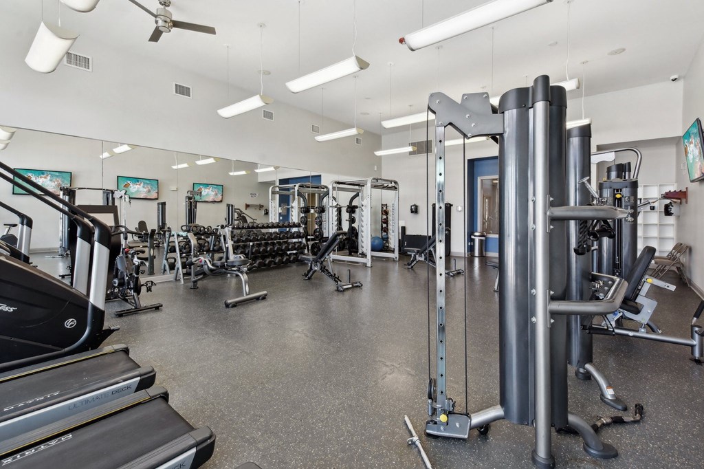 a gym with weights and cardio equipment on the floor and other gym equipment