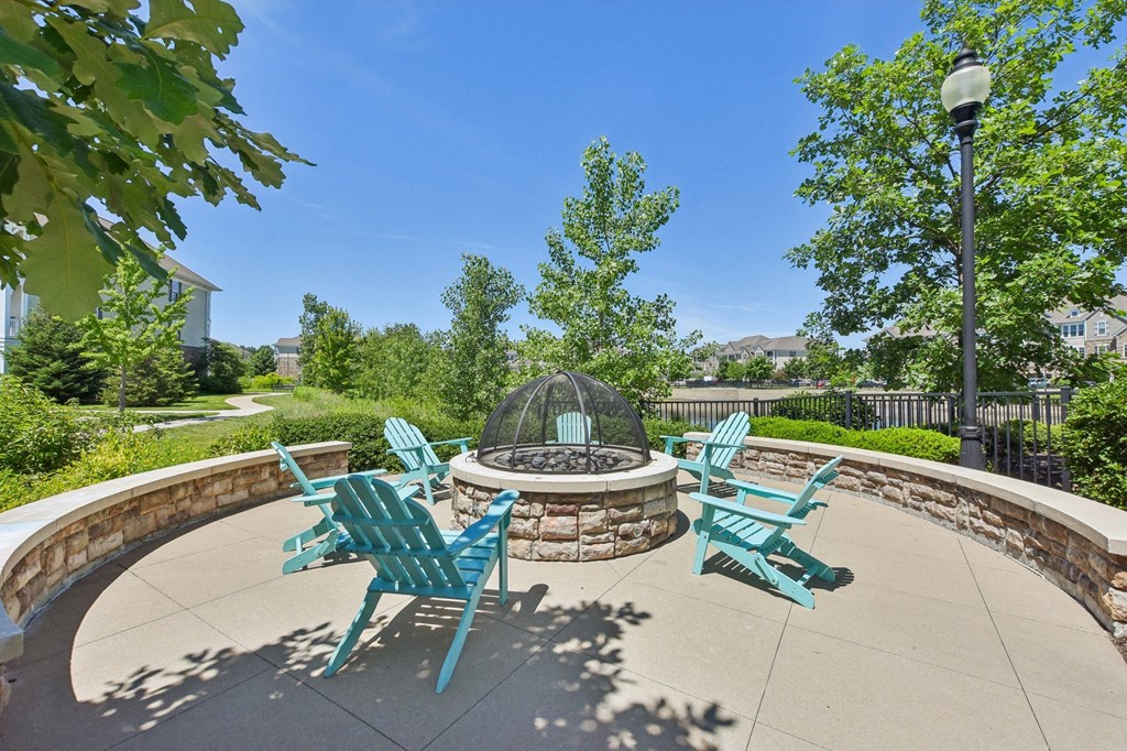 a patio with a fire pit and chairs