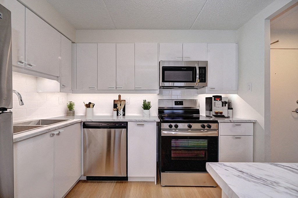 a white kitchen with stainless steel appliances and white cabinets