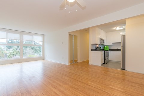 A kitchen with a refrigerator, microwave, and oven is visible from the living room.
