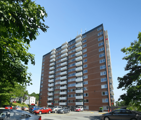 A tall apartment building with cars parked in front.