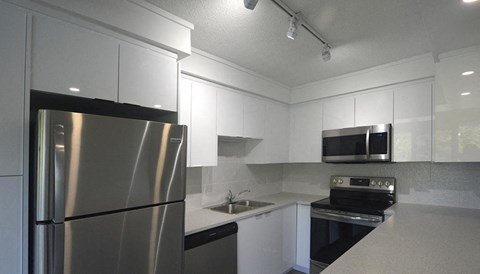 A modern kitchen with a stainless steel refrigerator and a microwave above the stove.