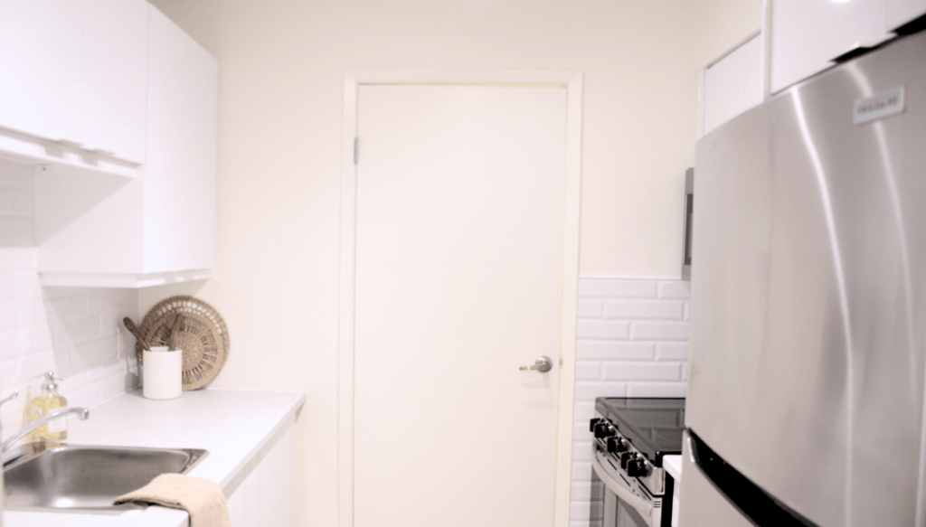 A white kitchen with a sink, stove, and refrigerator.