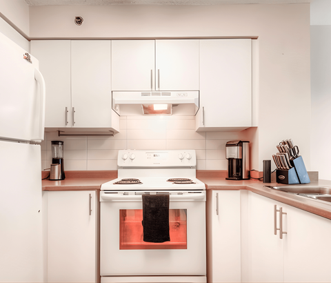 A white kitchen with a stove and a refrigerator.