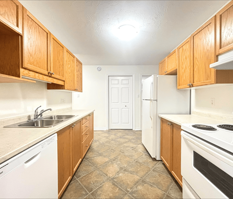 A kitchen with wooden cabinets and white appliances.