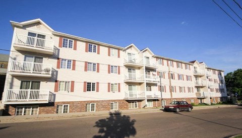 A red car is parked in front of a white and red building.