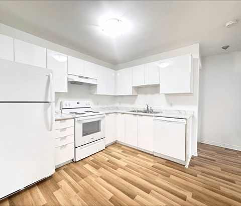 A white kitchen with wooden floors and white appliances.