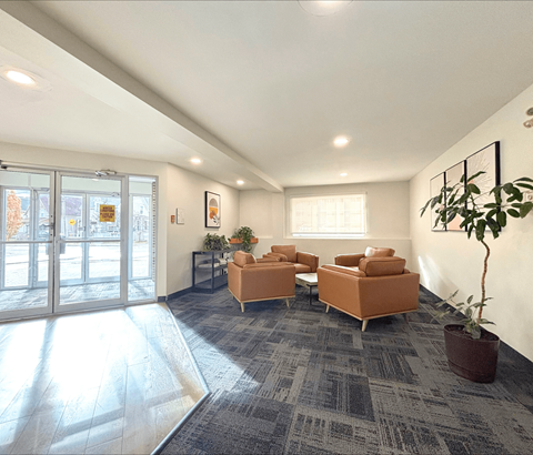 A spacious waiting room with a grey carpet and orange chairs.