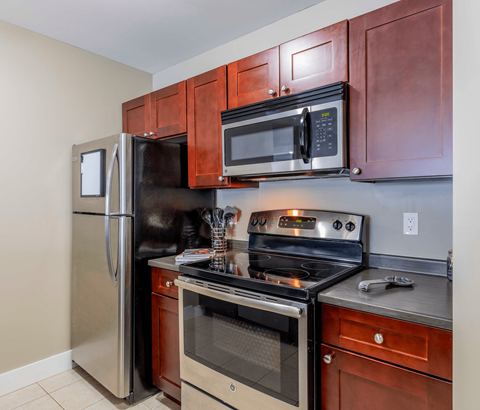 A kitchen with a refrigerator, oven, and microwave.