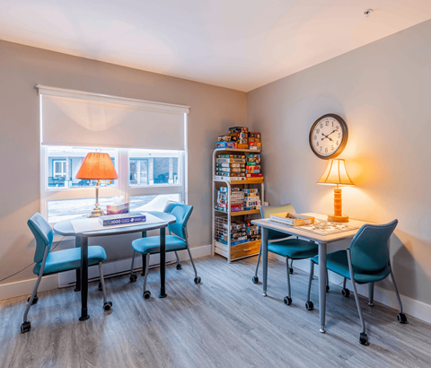 A room with a desk, chairs, and a clock on the wall.