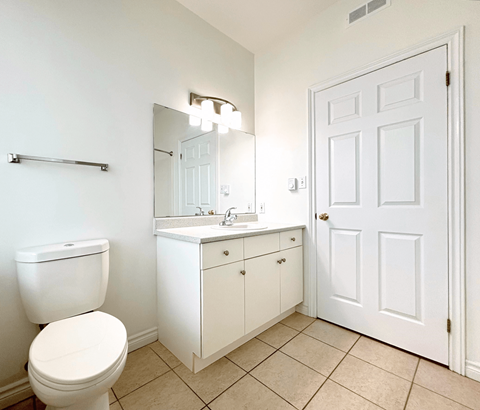 A white bathroom with a toilet, sink, and mirror.