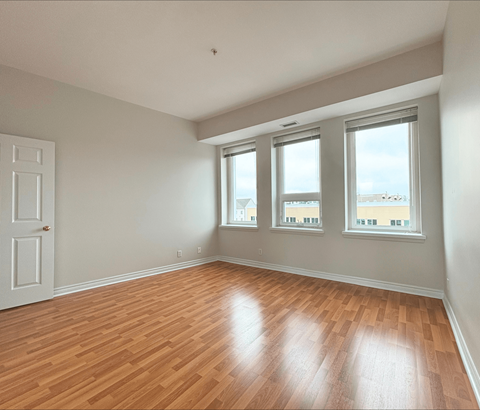 A room with wooden floors and three windows.