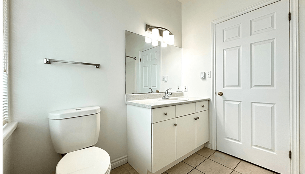 A white bathroom with a toilet, sink, and mirror.