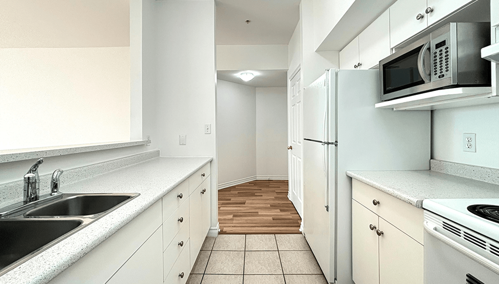 A kitchen with white cabinets and a black counter top.