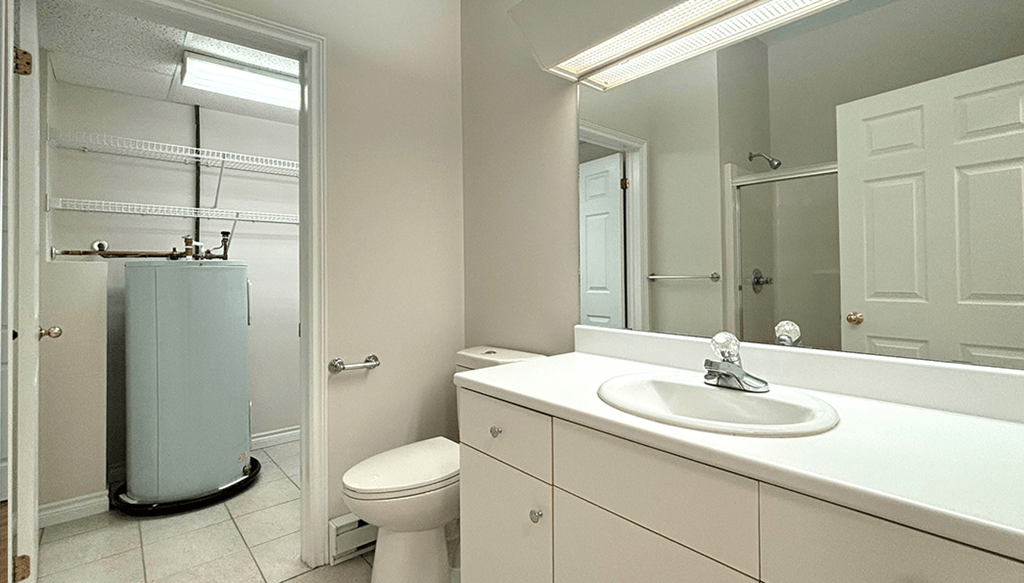 A bathroom with a white toilet, sink, and mirror.