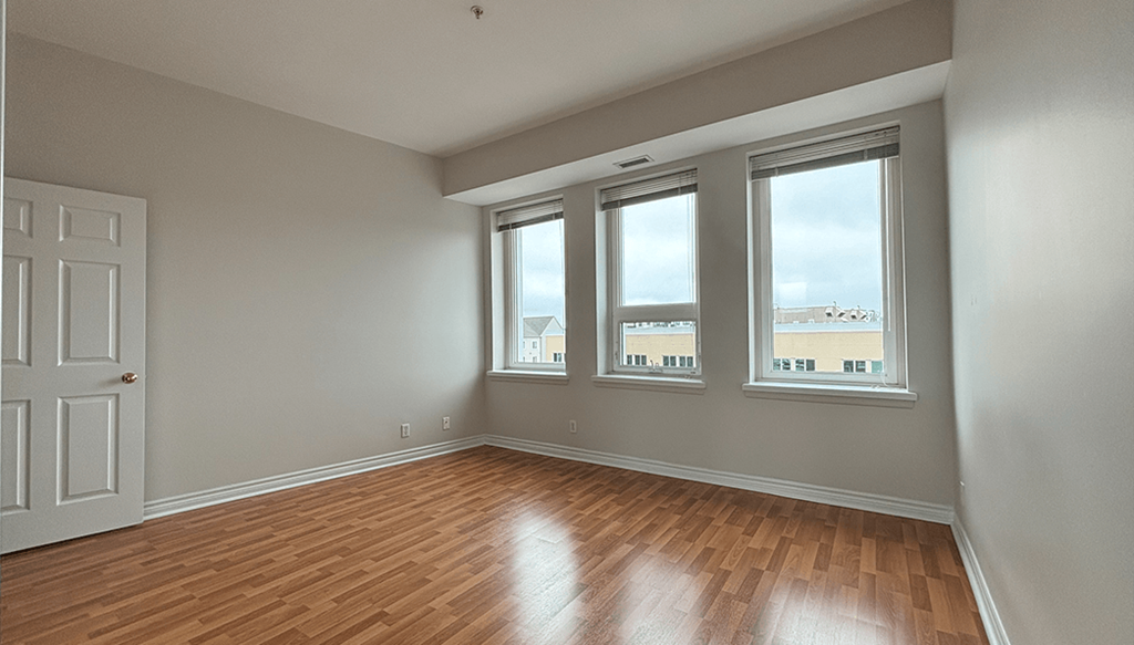 A room with wooden floors and three windows.