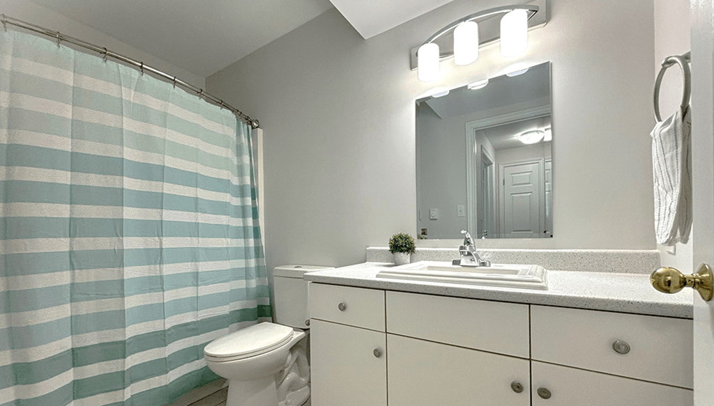 A bathroom with a white sink and a blue and white striped shower curtain.