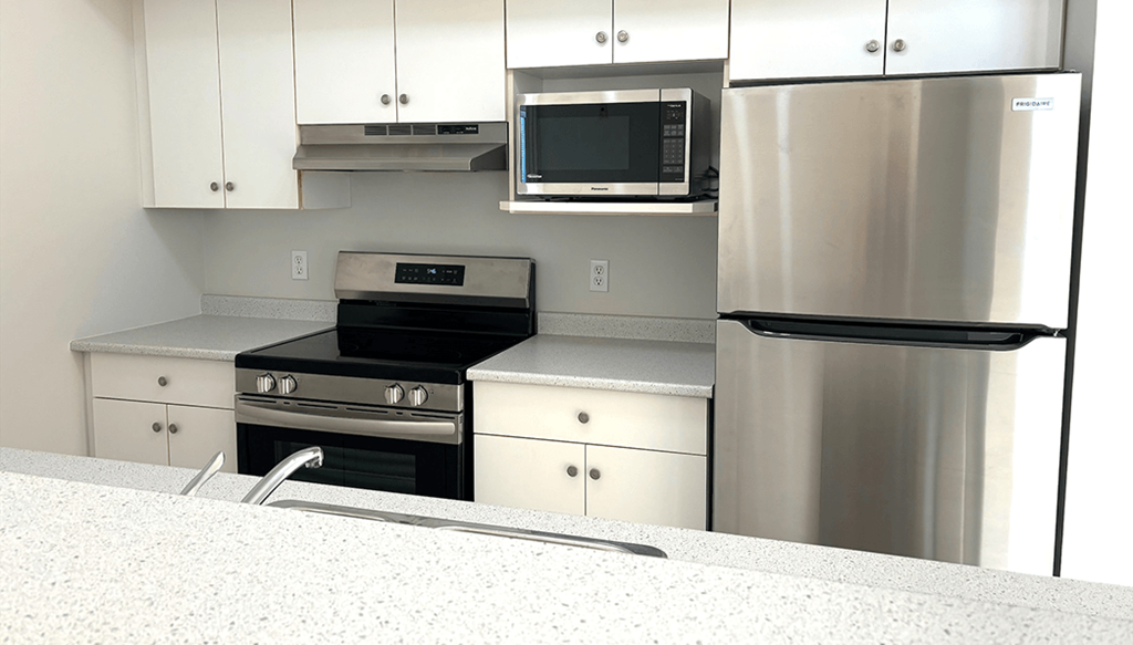 A modern kitchen with stainless steel appliances and white cabinets.