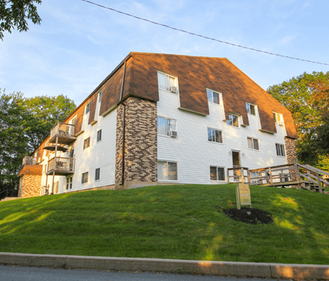 A white house with a brown roof and a stone chimney.