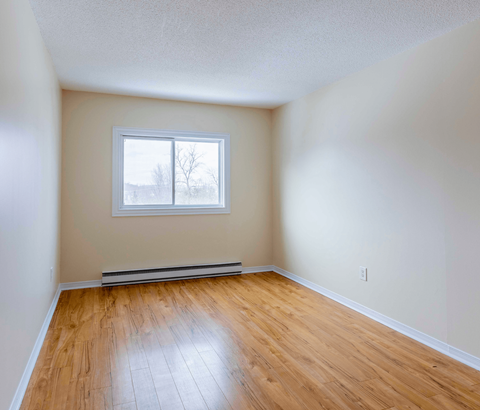 Empty room with a window and wooden floor.