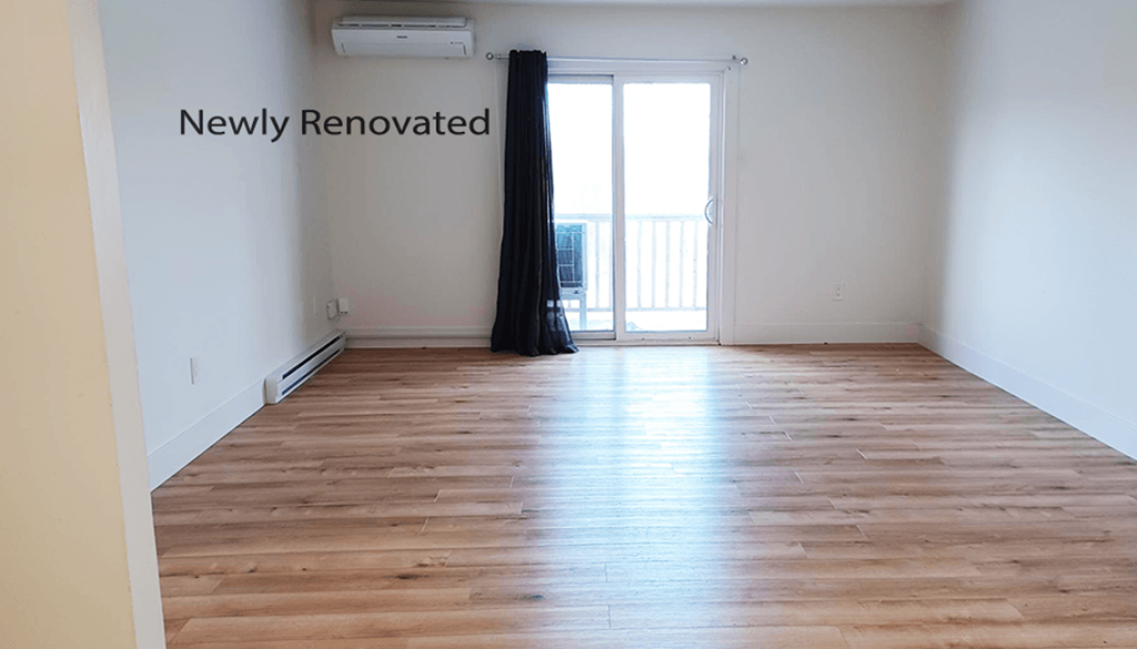 A room with wooden flooring and a window with a black curtain.