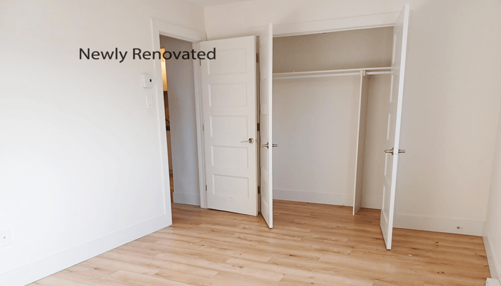 A newly renovated room with a white door and wooden flooring.