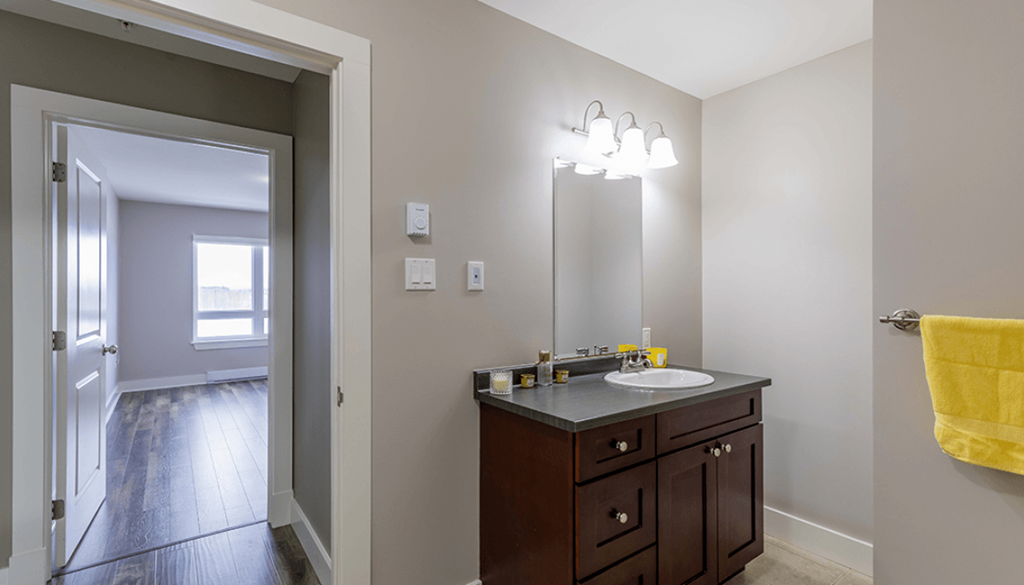 A bathroom with a sink, mirror, and a yellow towel.