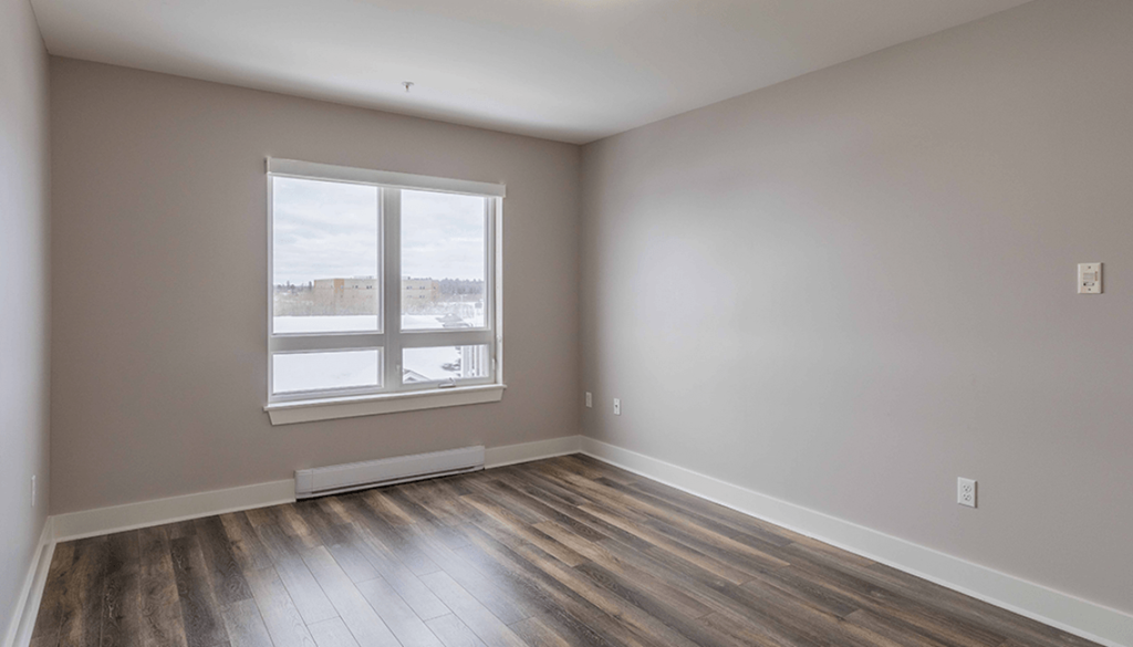 A room with a window and wooden flooring.