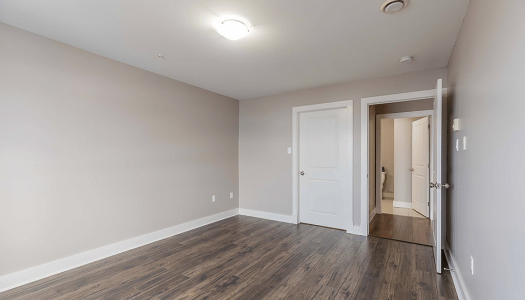A room with a white door and a brown floor.