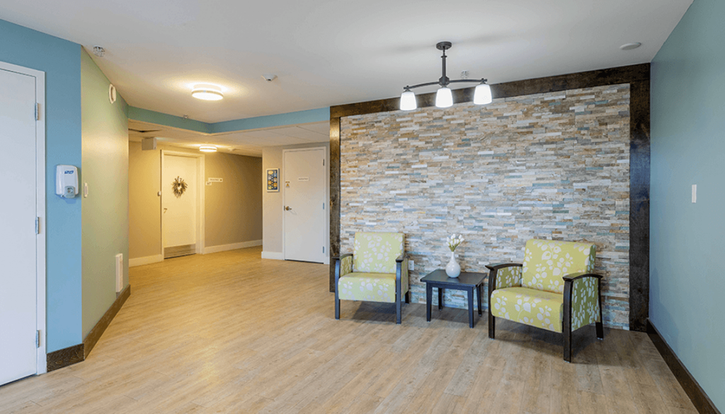 A room with a stone wall and two chairs.