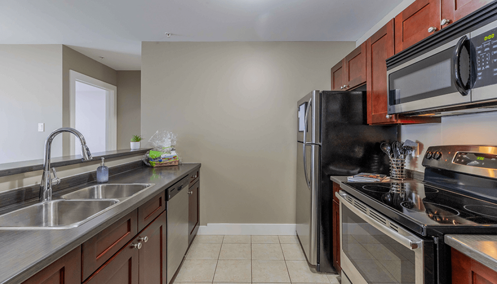 A kitchen with a black refrigerator and stove top oven.