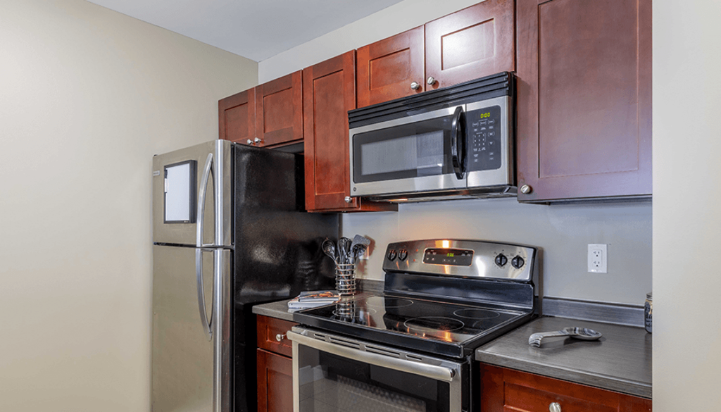 A kitchen with a refrigerator, microwave, oven, and stove.